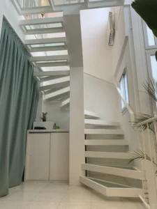 Escalera moderna de hierro blanco con escalones de vidrio transparente diseñada por Nico Berreta.